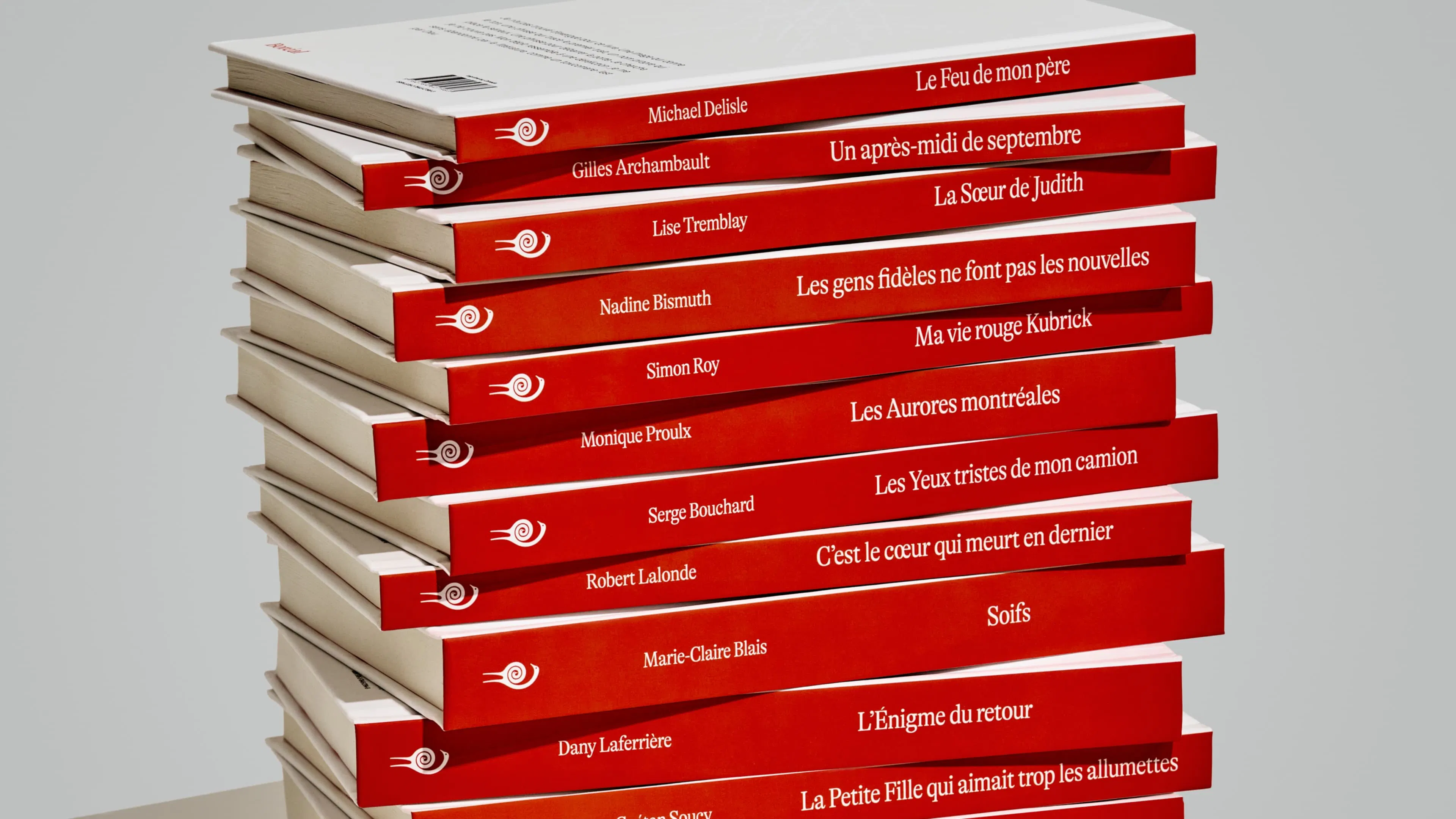 A stack of books with red spines featuring French titles is neatly arranged on a beige, modern geometric table against a gray background.