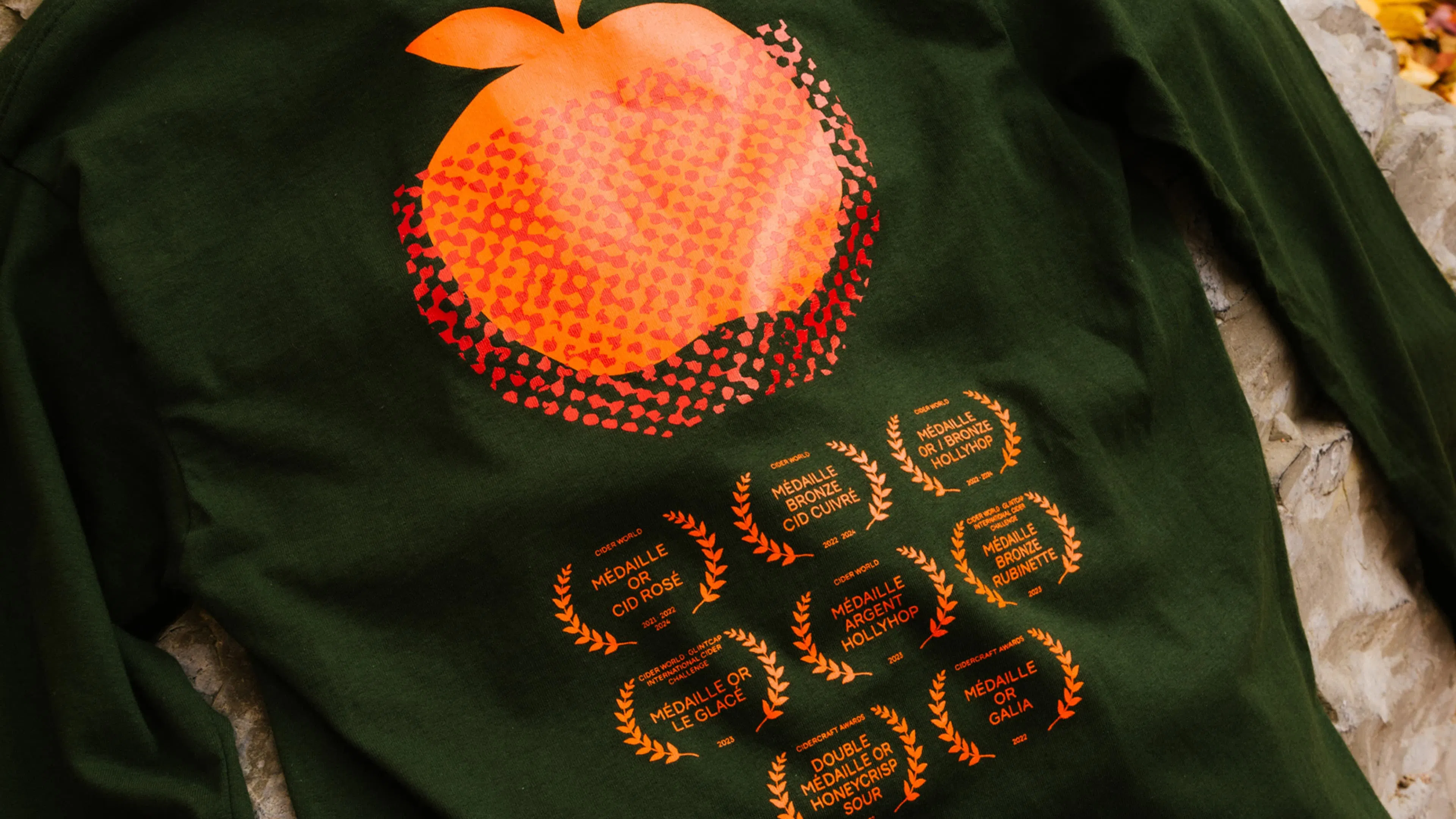 Green jacket with a large, stylized orange apple and nine award symbols on the back.