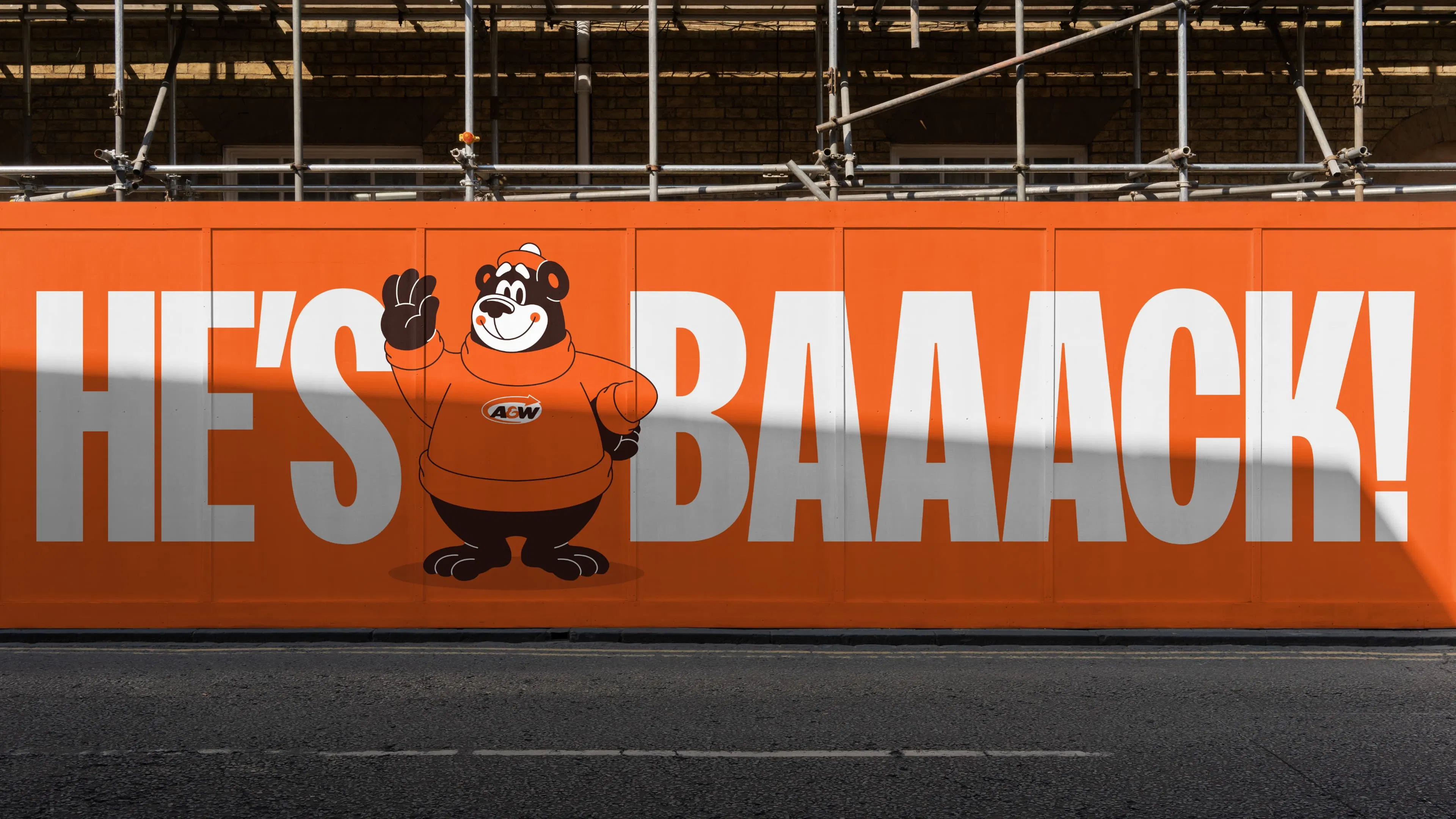 Orange billboard with a cartoon bear wearing an A&W sweater, waving. A large white text reads "HE'S BAAACK!"