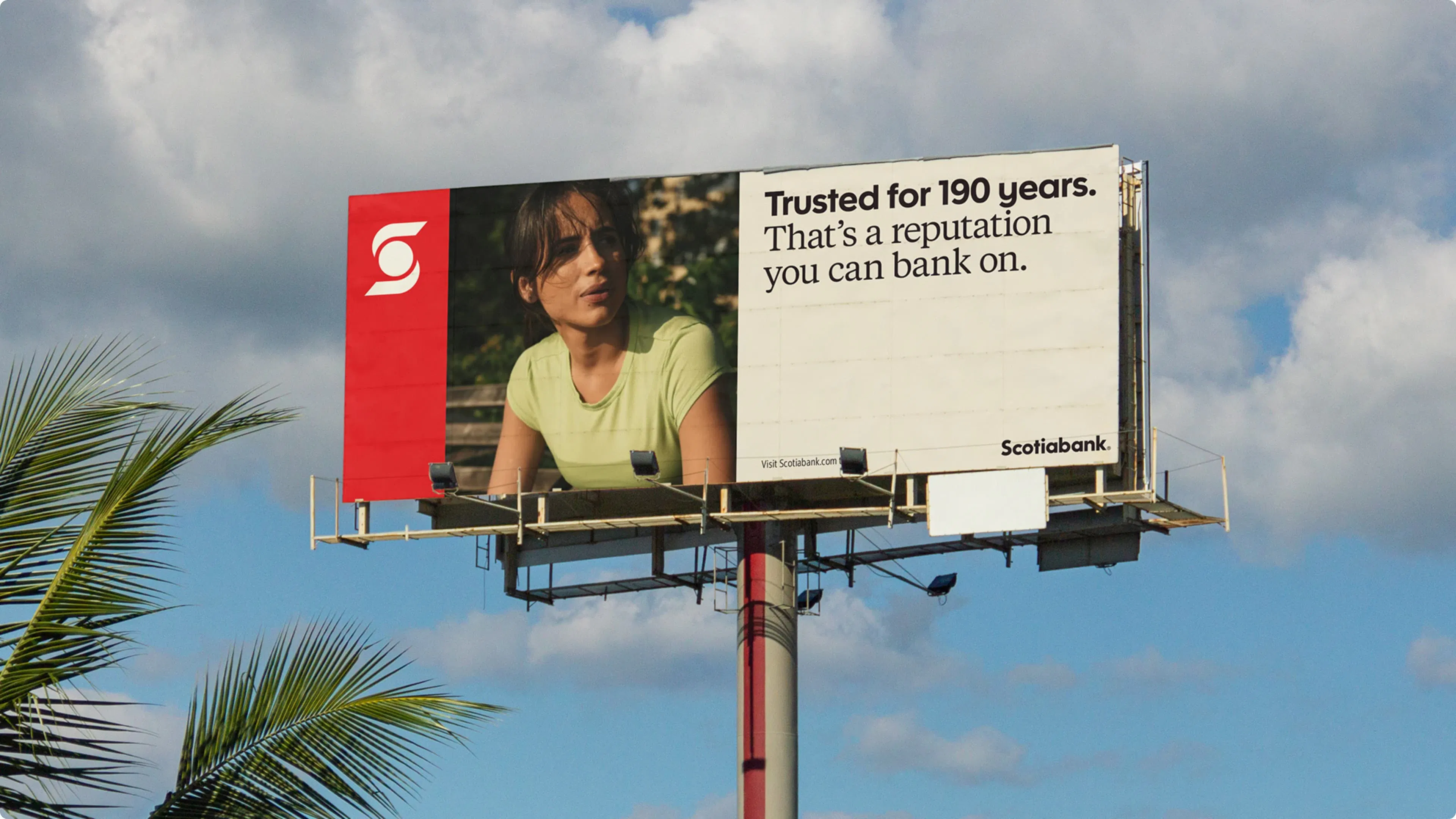 Billboard under a blue sky with clouds, featuring a thoughtful woman in a light green shirt. Text reads, "Trusted for 190 years. That's a reputation you can bank on." Scotiabank logo on the left.