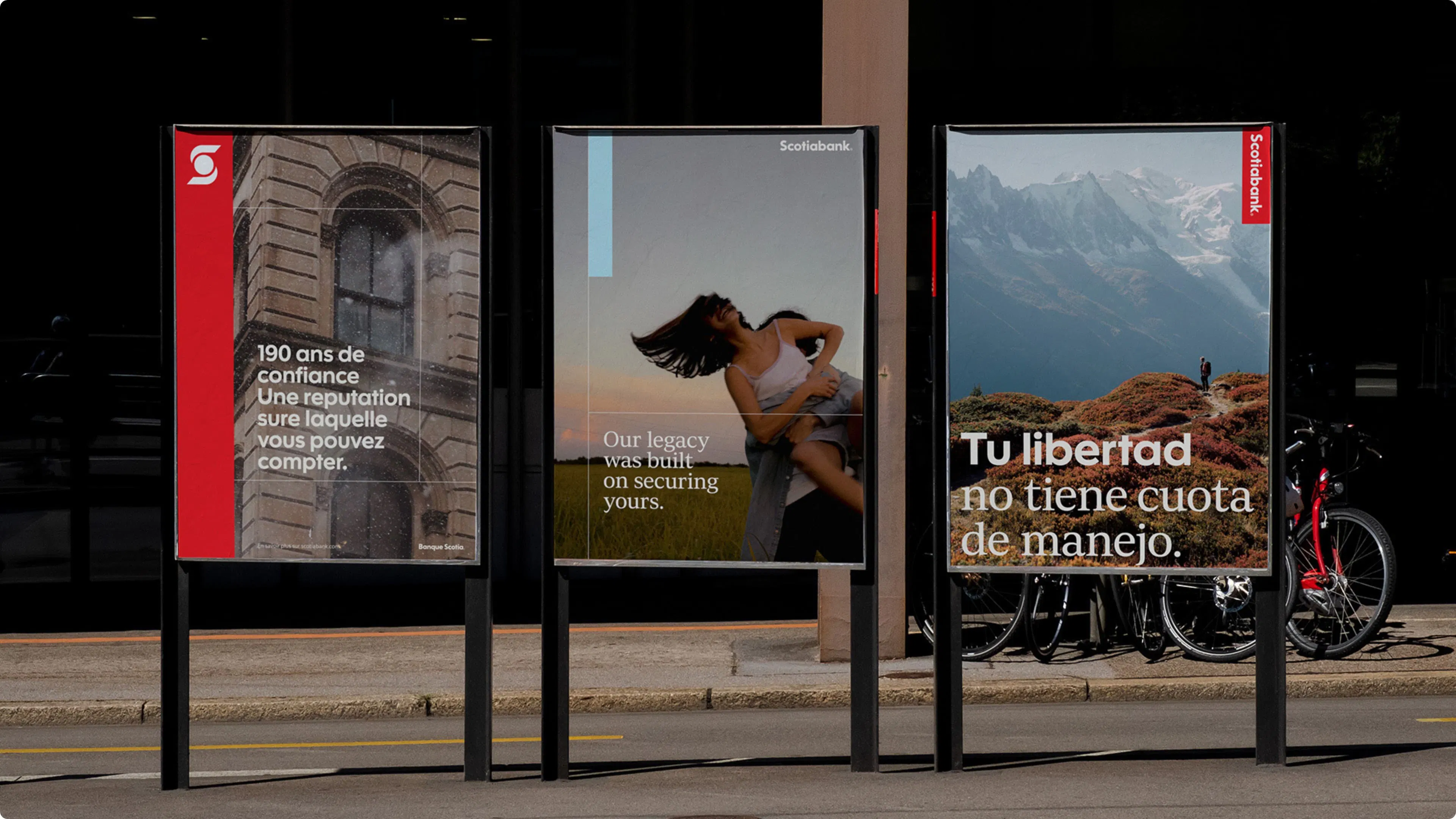 Three outdoor Scotiabank ads in different languages. The French ad shows a brick archway, the English ad features a human couple hugging, and the Spanish ad displays a mountainous landscape.