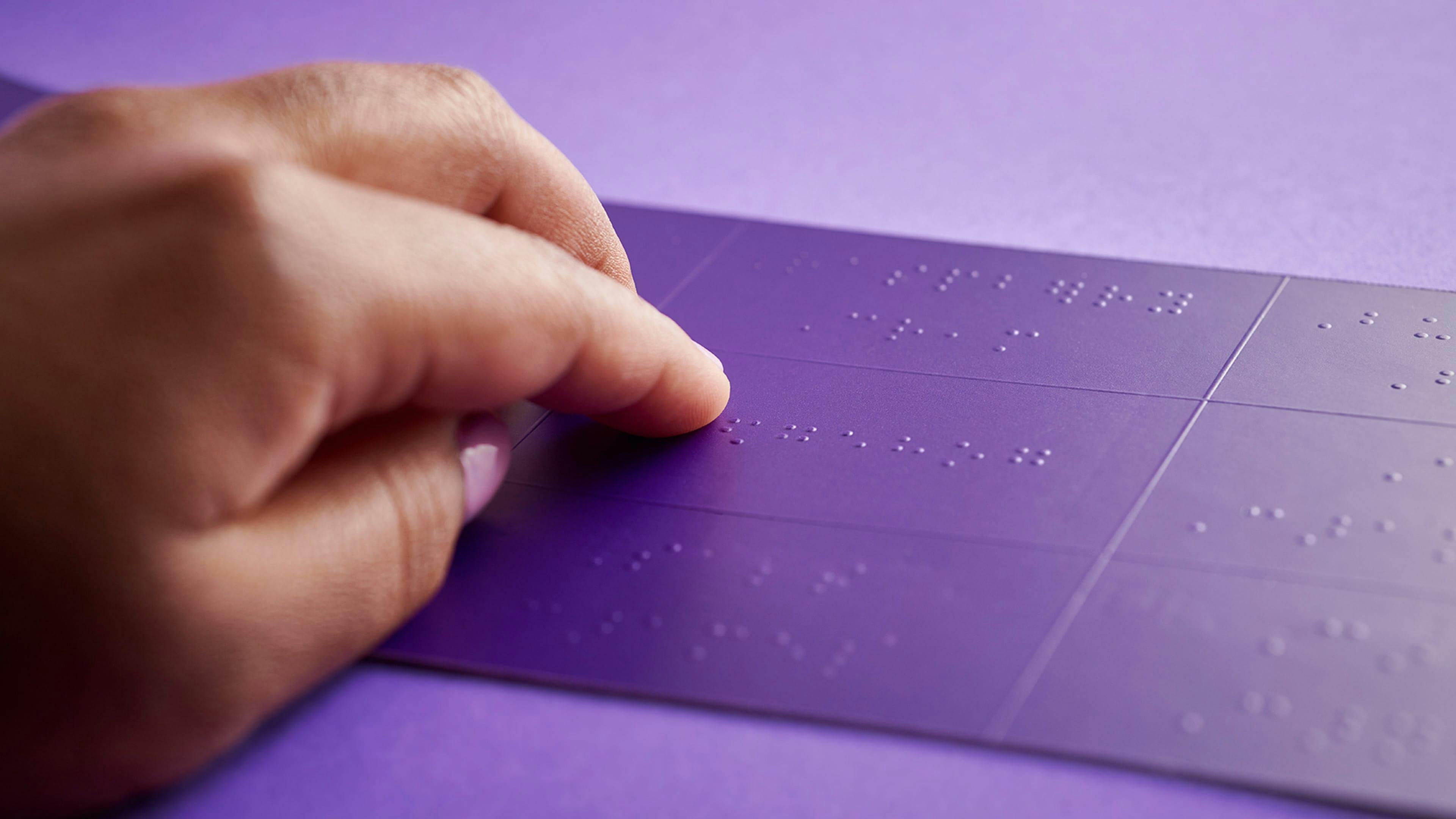 Fingers reading braille on Purdy's box. 