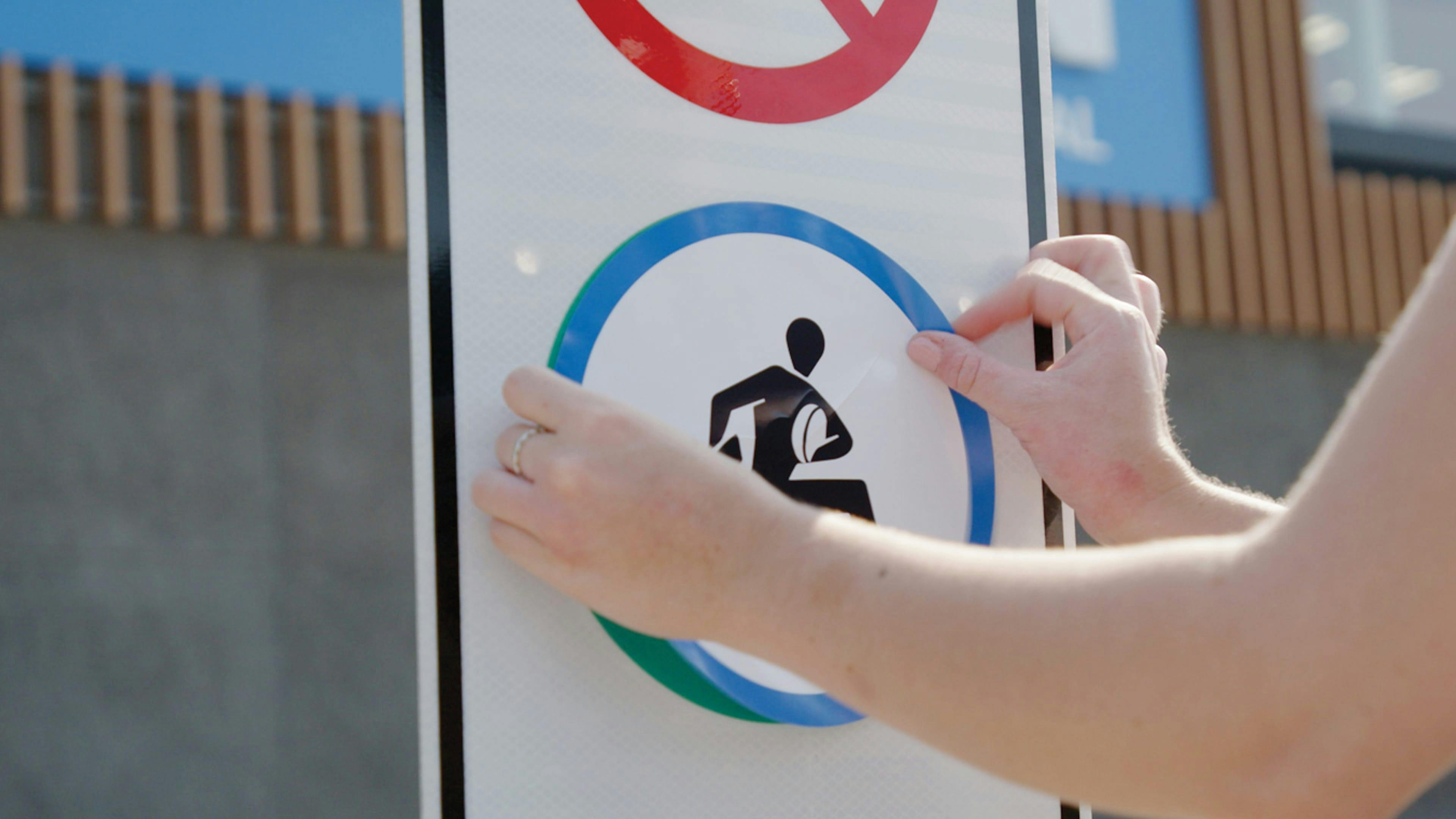 Placing an ability signs sticker on a handicap parking sign. 