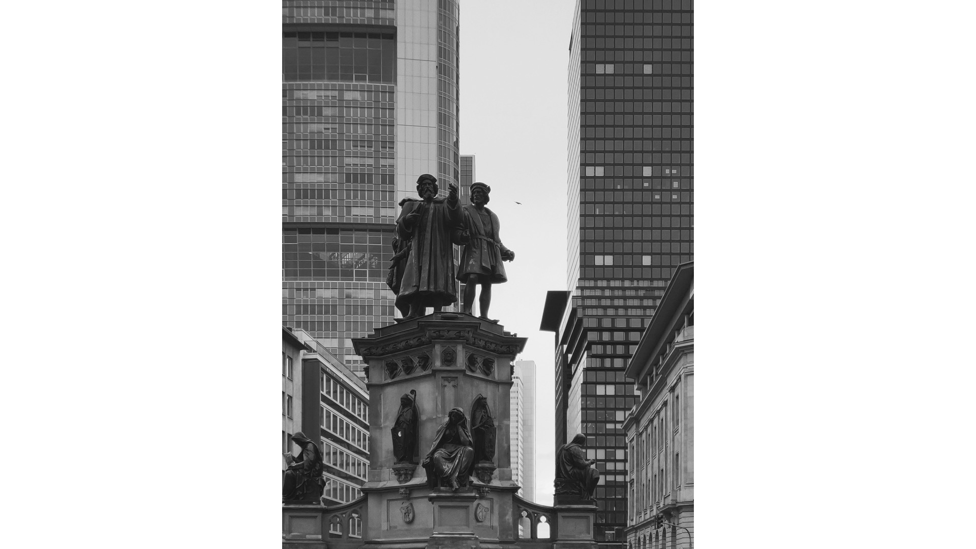 Blick auf eine Statue zwischen Wolkenkratzern.