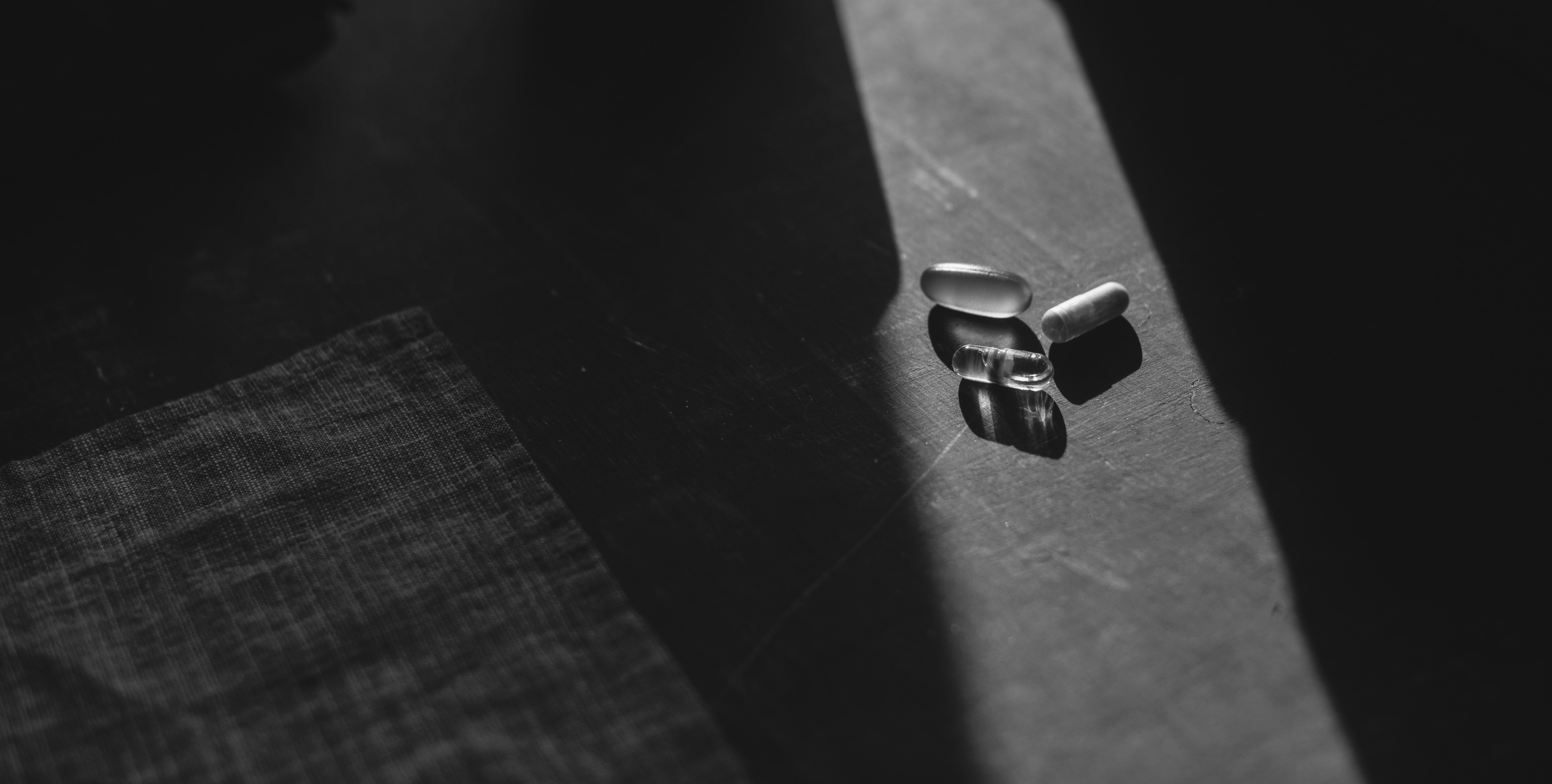 Tabletten und Kapseln, die von einem hellen Lichtstrahl beleuchtet werden.