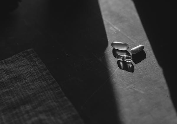 Tabletten und Kapseln, die von einem hellen Lichtstrahl beleuchtet werden.