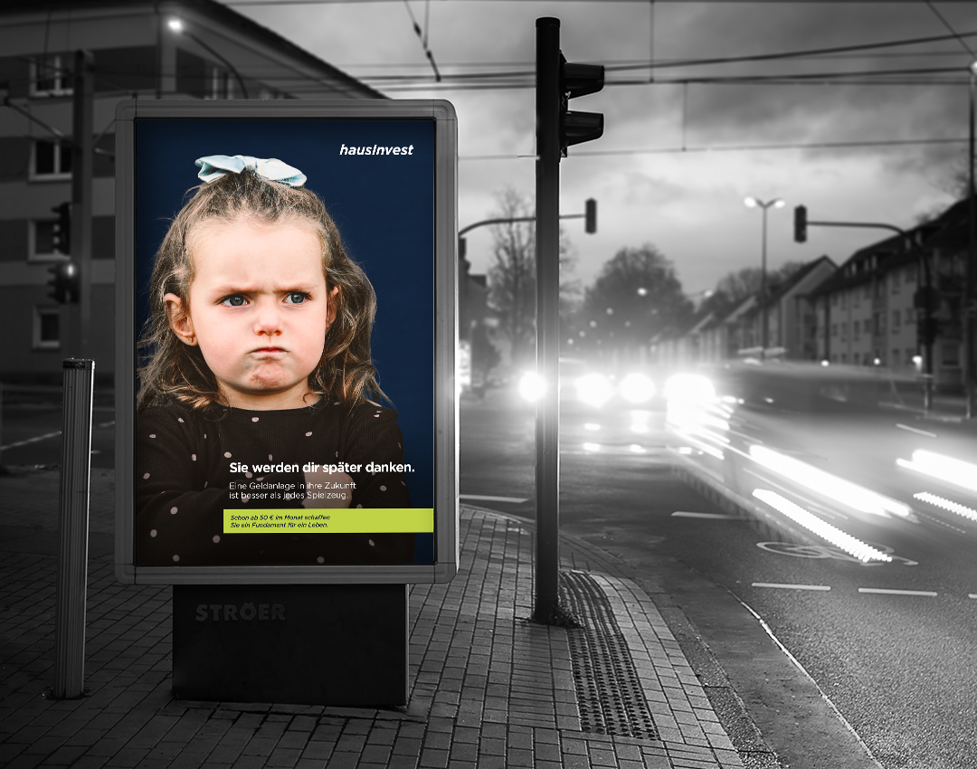 Leuchtendes Werbeplakat an einer großen Straße, das ein Motiv der hausInvest Werbekampagne für Eltern zeigt.
