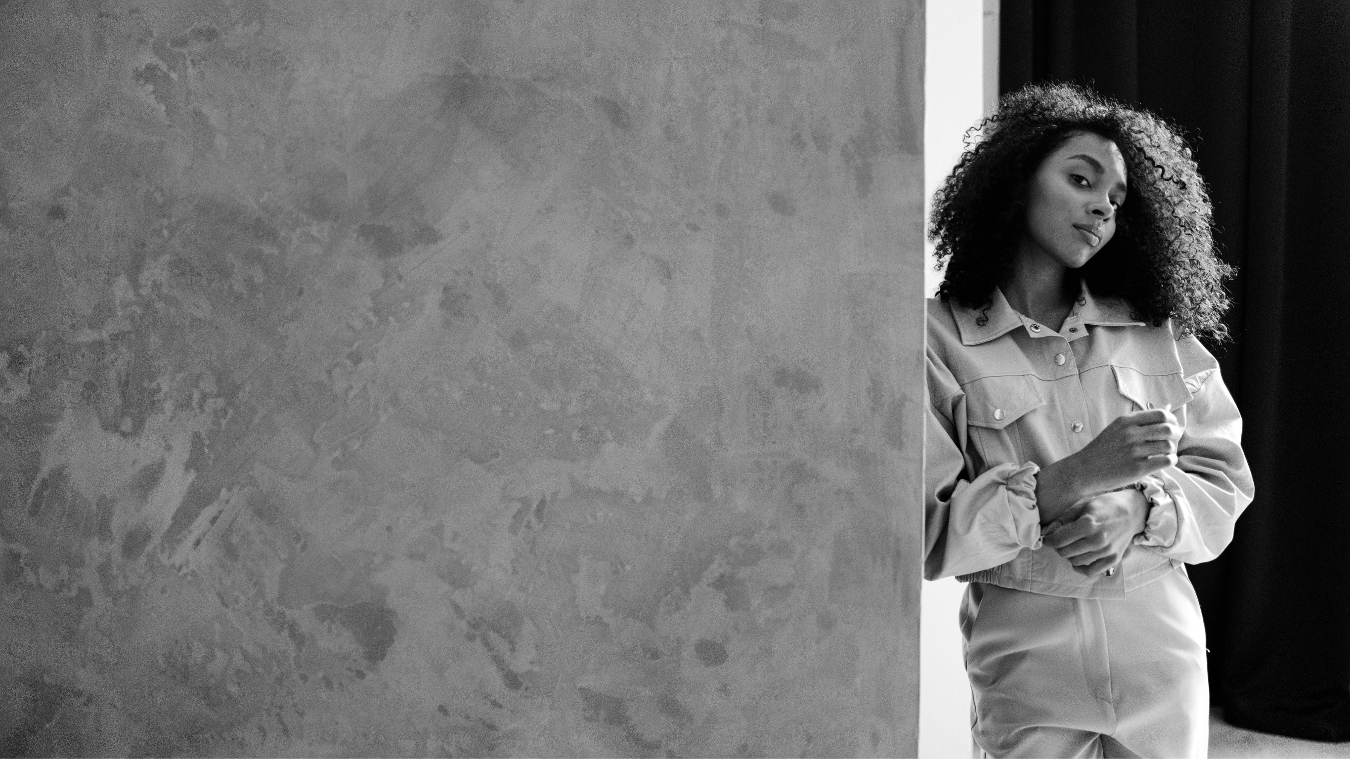 Eine Frau lehnt an einer Wand und blickt von oben in Richtung Kamera.