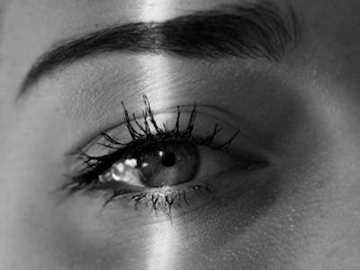 Nahaufnahme von einem Auge, das von einem Lichtstrahl beleuchtet wird.