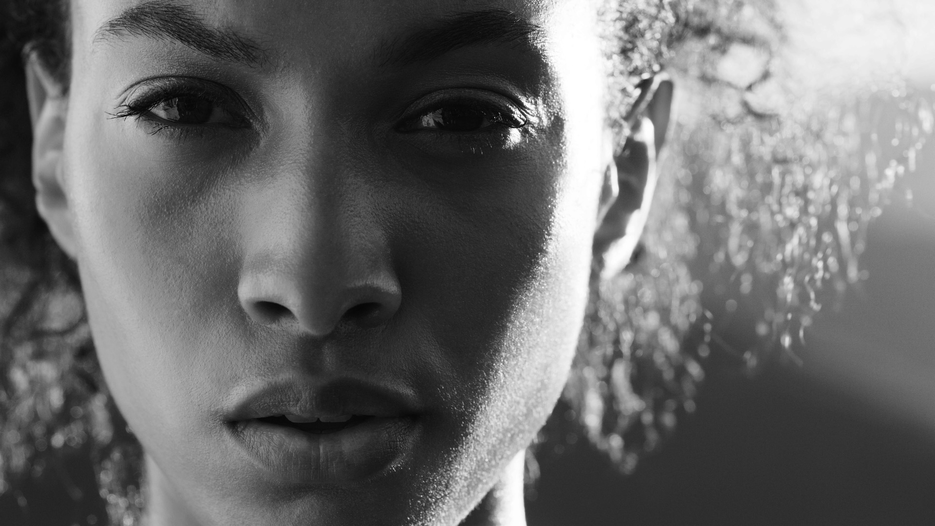 Nahaufnahme von einer Frau, ihr Gesicht wird seitlich von der Sonne angeleuchtet.