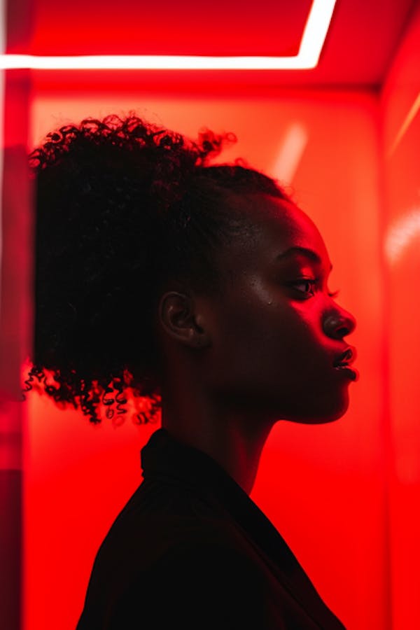 Eine Frau von der Seite, die in einem rot beleuchteten Raum steht.