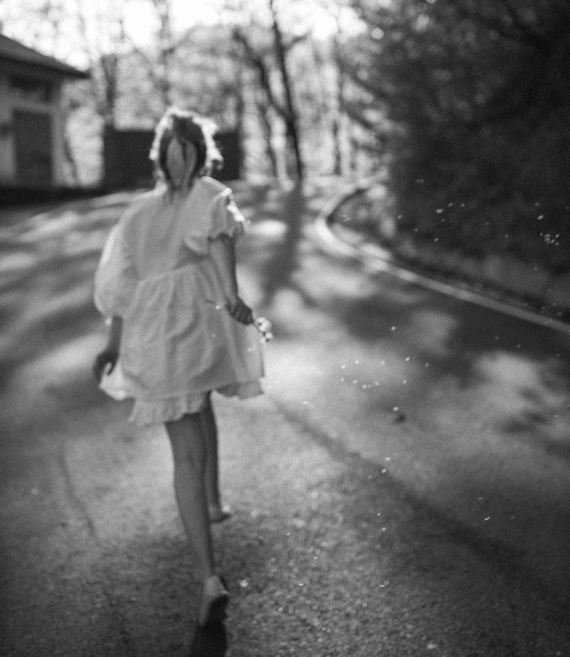 Rennendes Mädchen in einem Kleid von hinten auf der Straße.