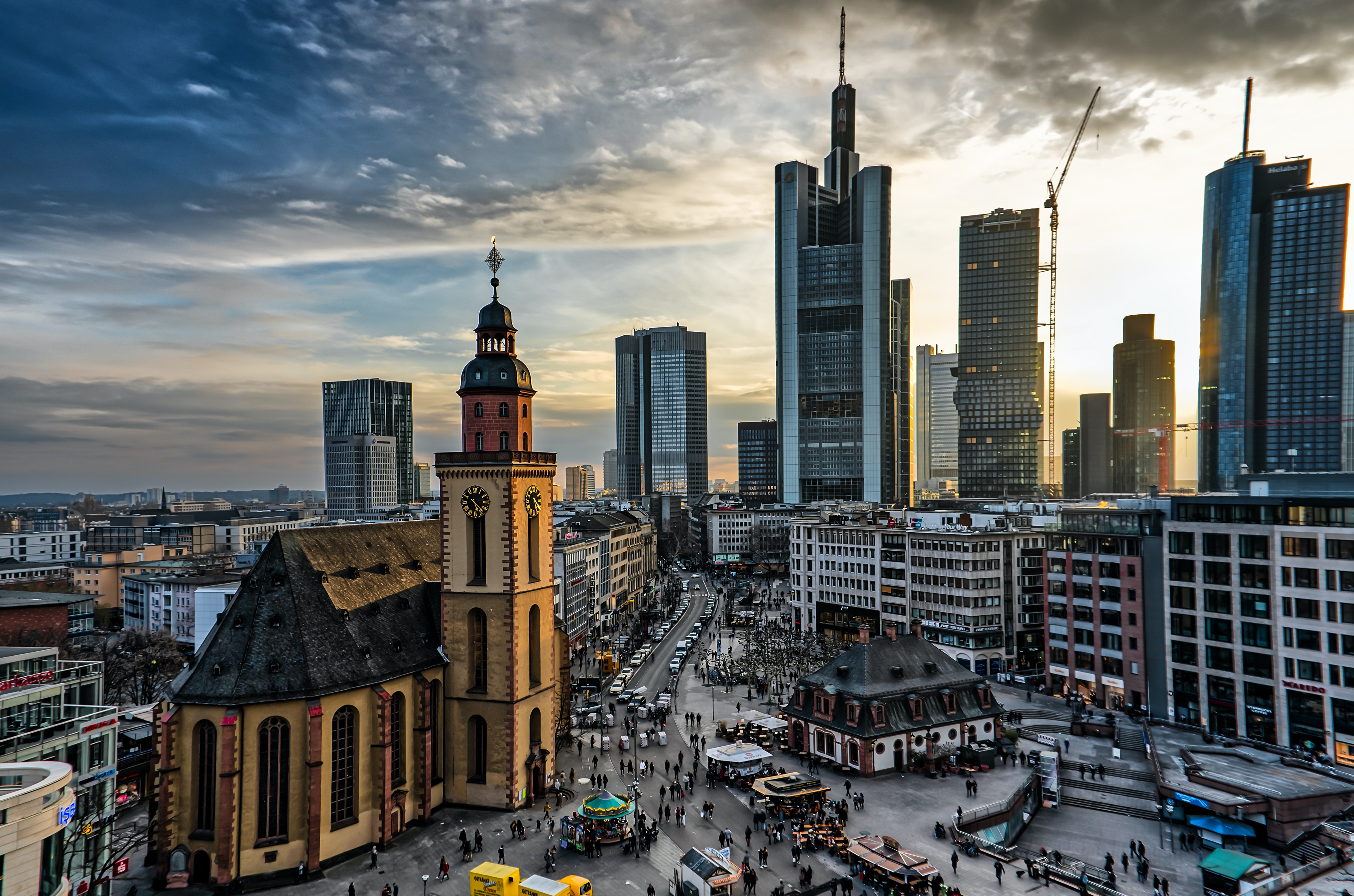 Blick auf eine Skyline mit Wolkenkratzern vor einem leicht bewölkten Himmel mit Abendsonne.