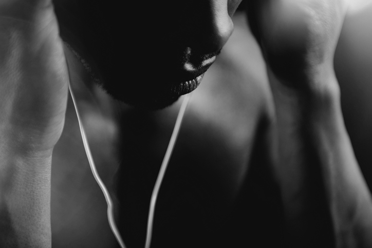 Atmosphärische Nahaufnahme von einem Mann, Nase und Mund im Fokus, in den Händen hält er In-Ear-Kopfhörer.