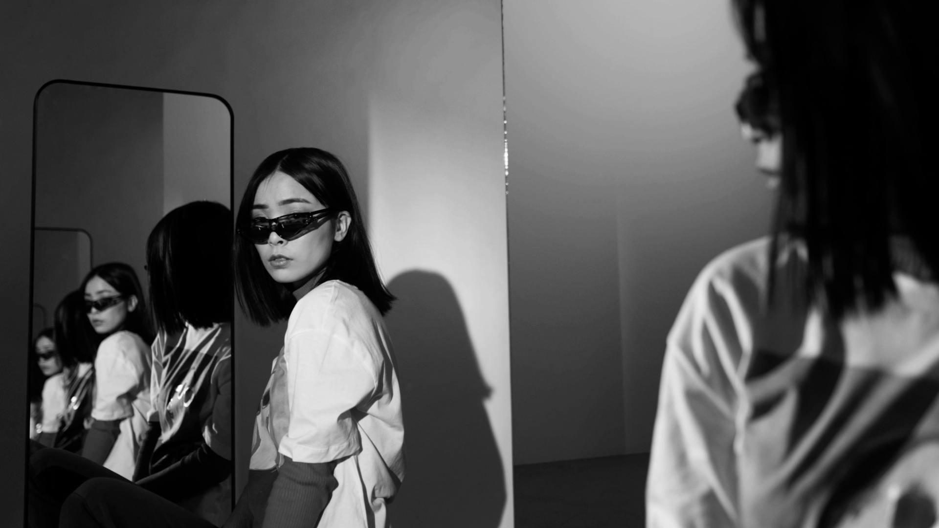 Eine Frau mit Sonnenbrille steht vor einem Spiegel.