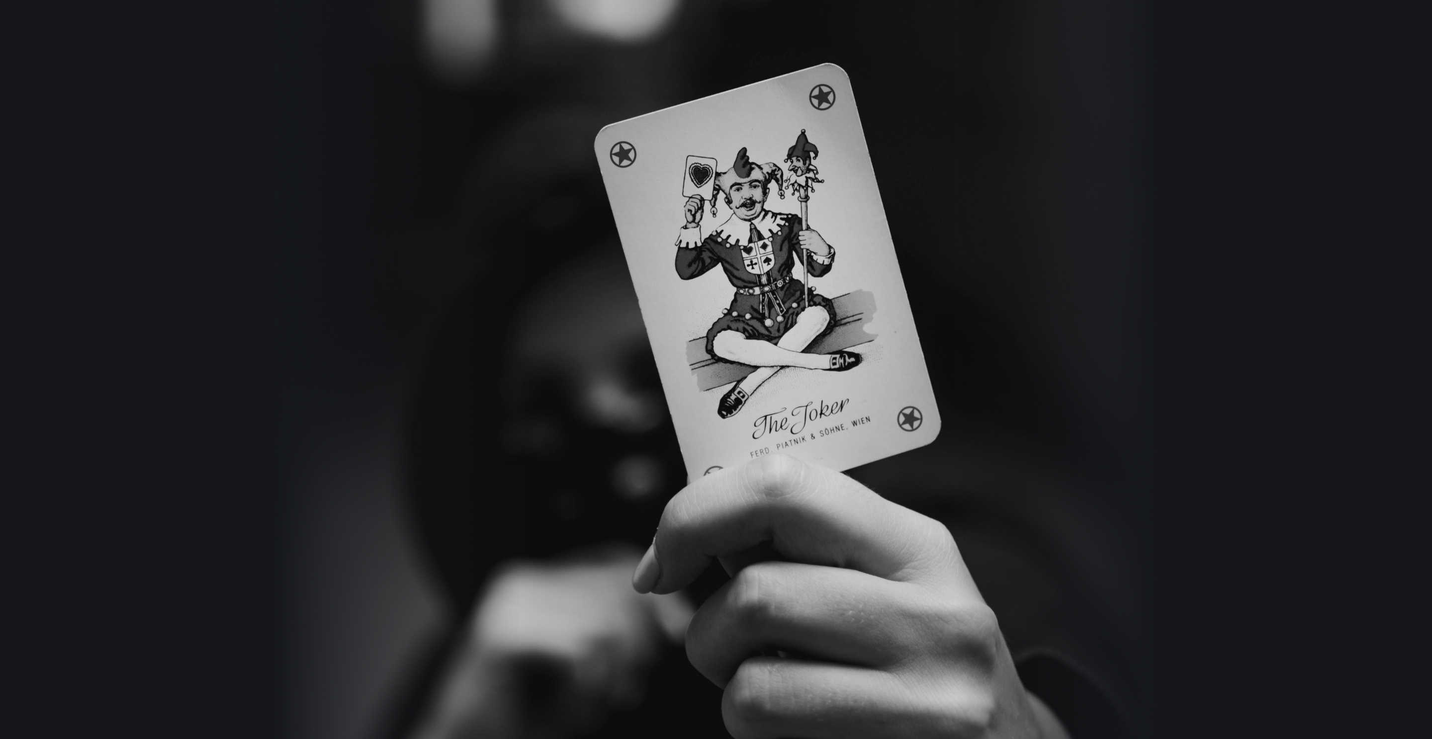 Eine verschwommene Person, der Fokus liegt auf einer Joker-Karte, die sie hochhält.