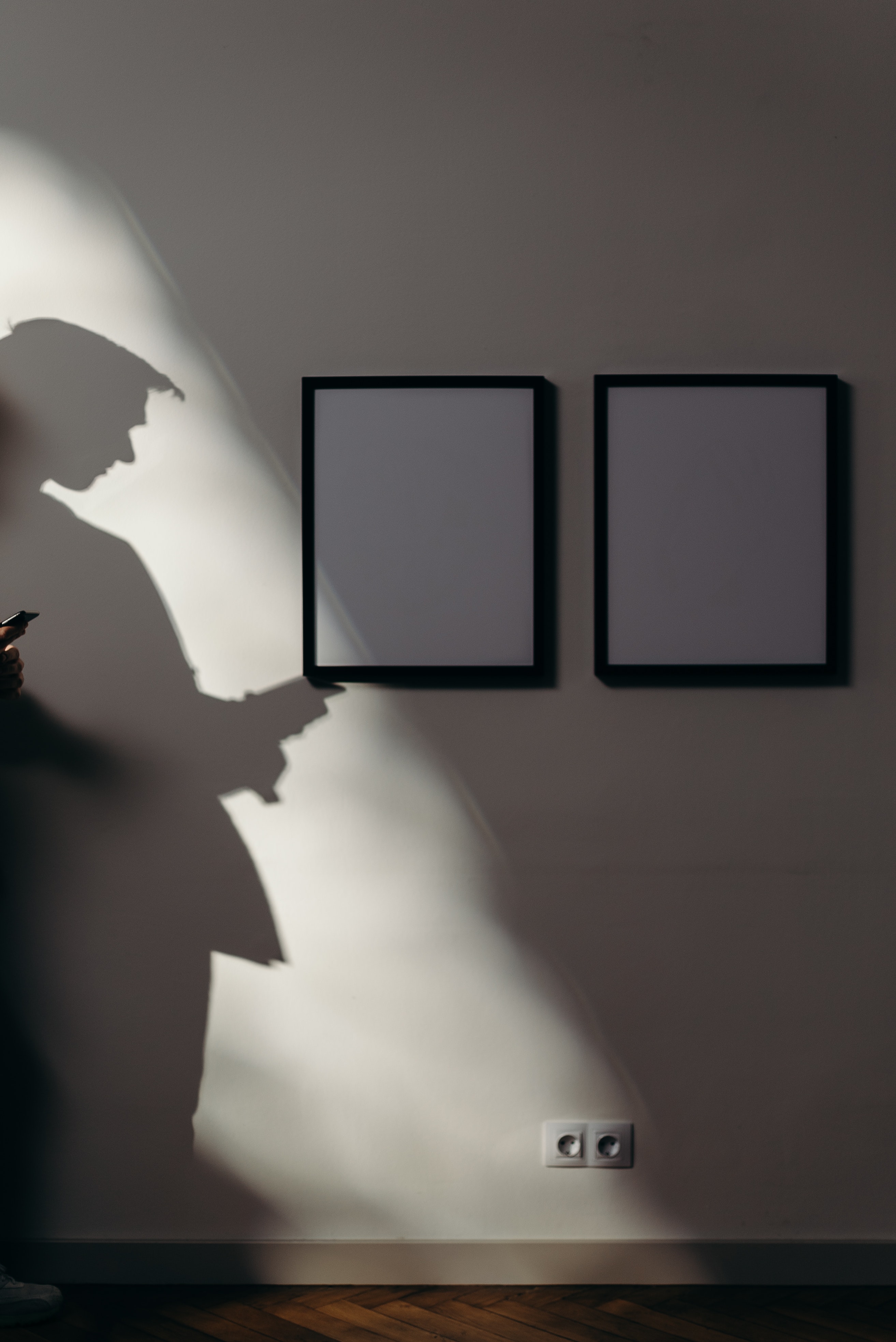 Schatten eines Mannes vor Wand mit aufgehängten Bildern.