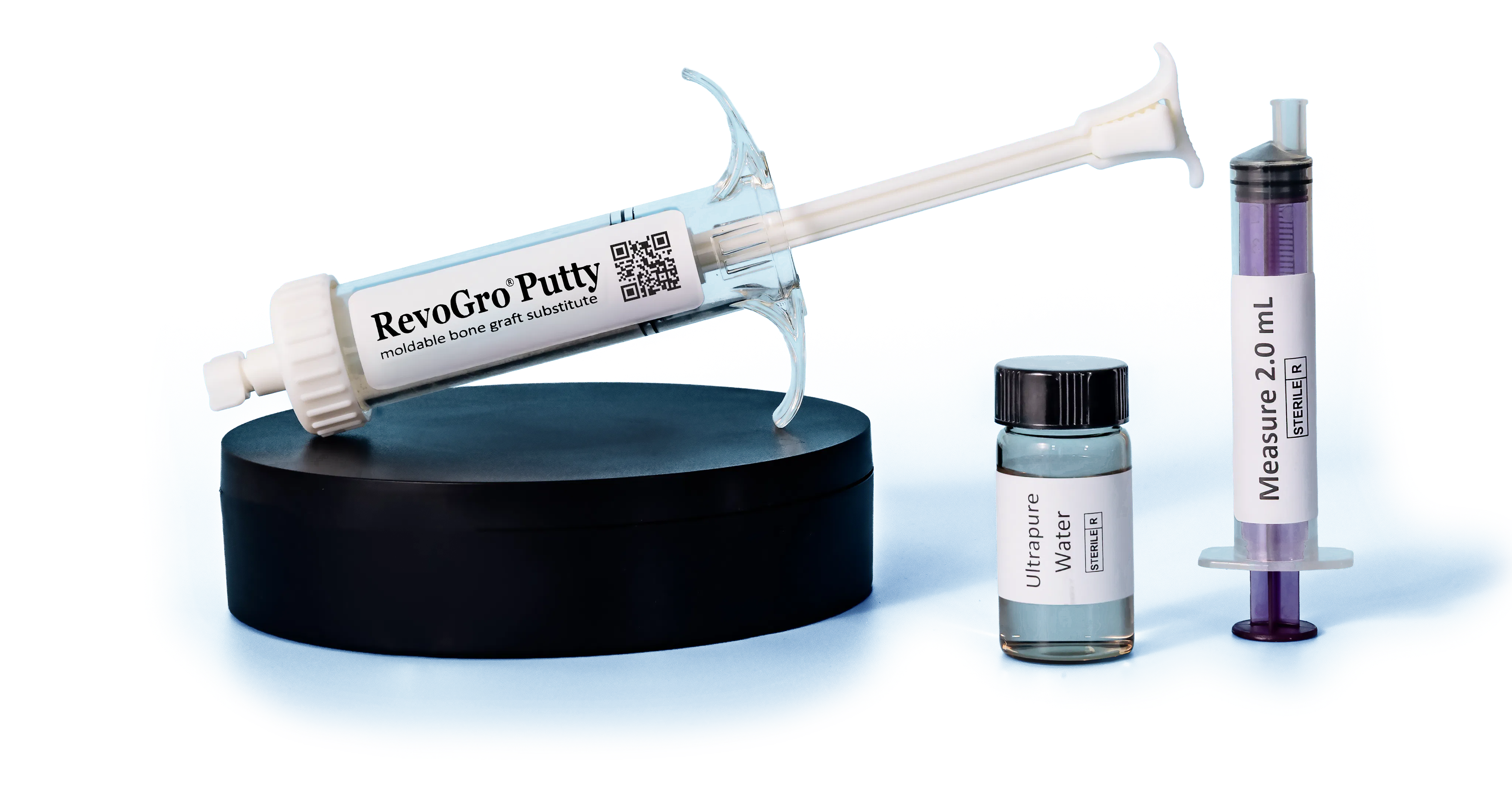 RevoGro Putty syringe on a black display stand beside a vial of ultrapure water and a 2.0 mL measuring syringe