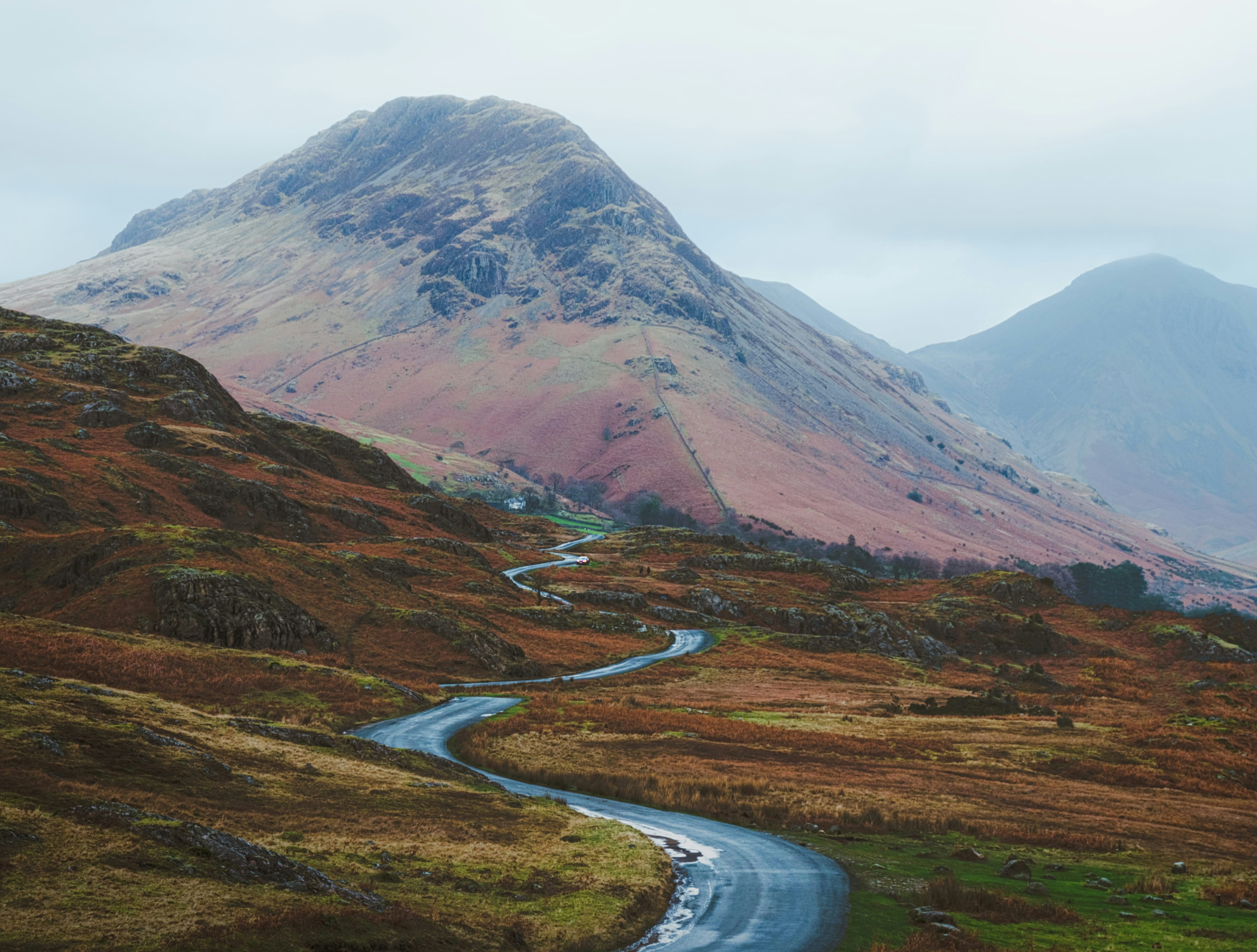 Long winding road in remote countryside heading towards large hill in the background