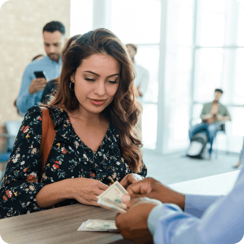 women being given cash by a bank teller