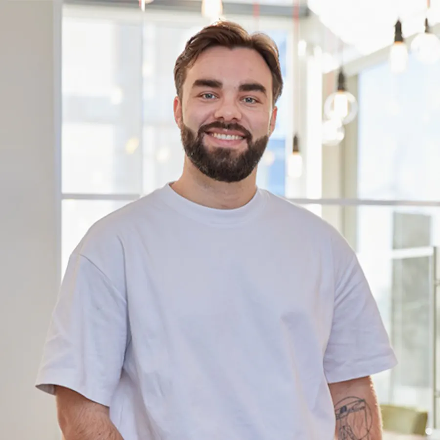 Portret van Richard Verbeek: lachend, met baard, in een lichtgrijs T-shirt in een lichte ruimte