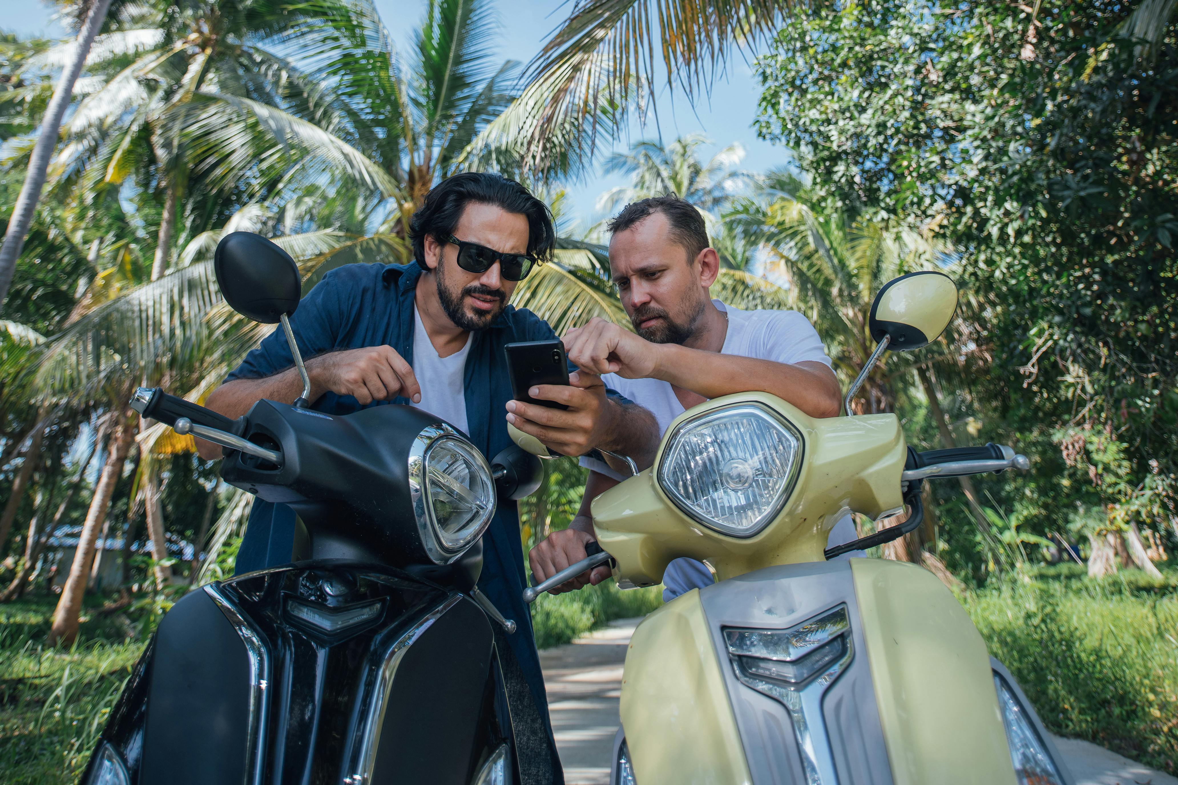 Two men on motorcycles planning and looking at their travel route on a mobile GPS and navigation app