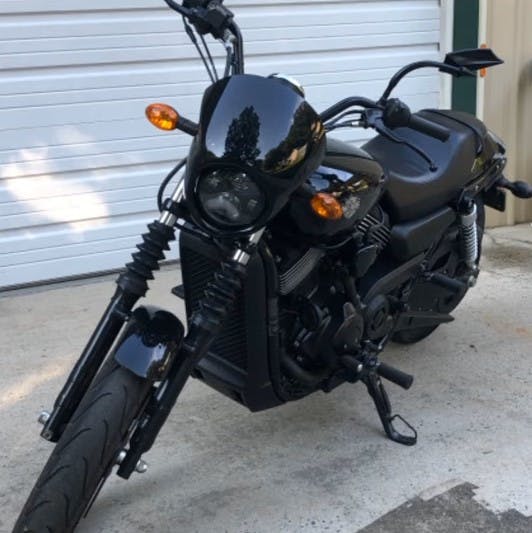 picture of a black harley davidson street rod parked in front of a garage door