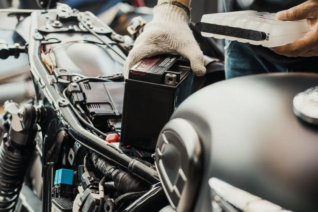 Imagen que muestra el reemplazo de la batería de motocicleta y sosteniendo un paquete ácido o un paquete electrolítico sellado para preparar el llenado de la batería Mantenimiento DIY de baterías de motocicleta