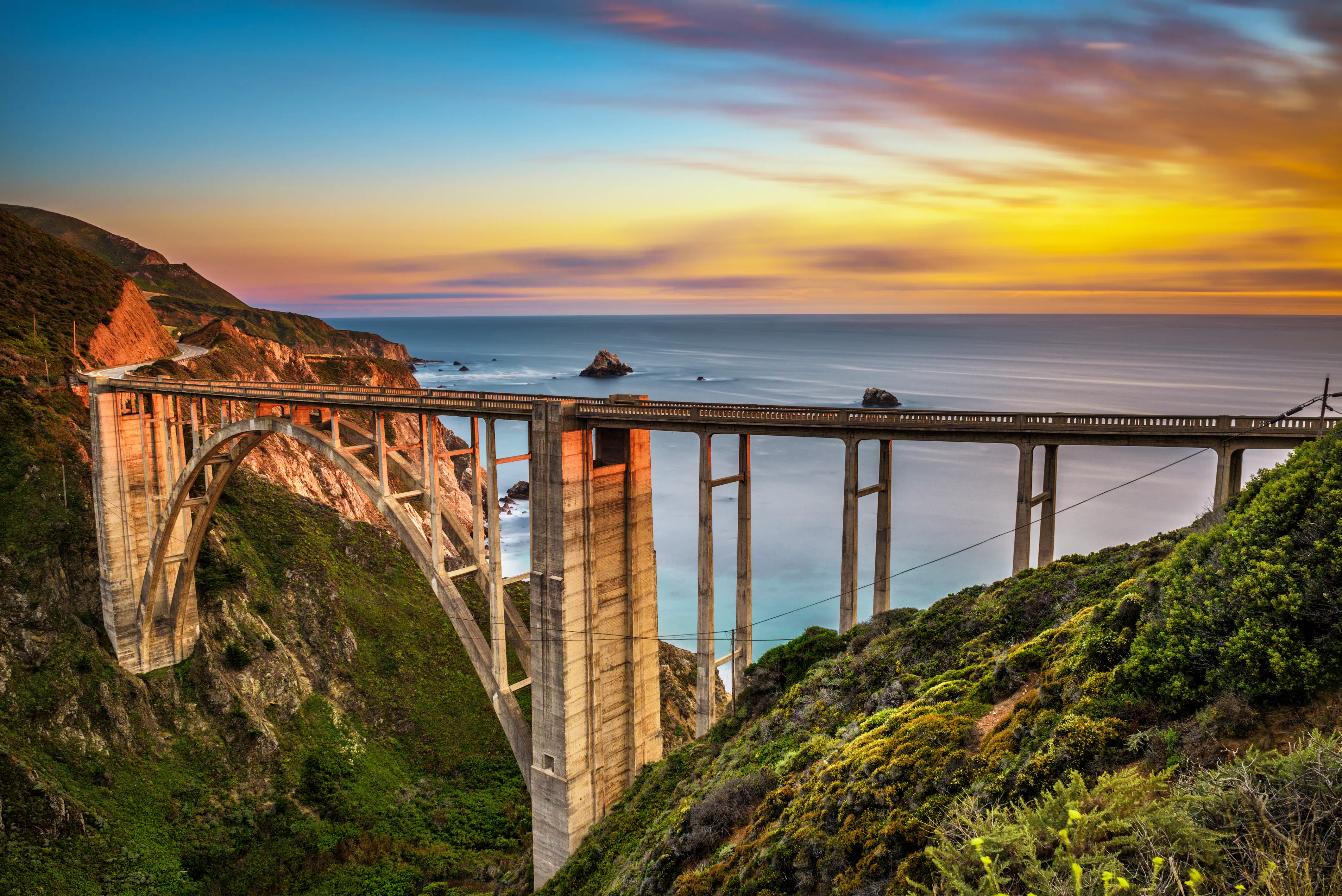Vista de una pintoresca ruta en motocicleta a lo largo de la Pacific Coast Highway y el Puente Bixby al atardecer