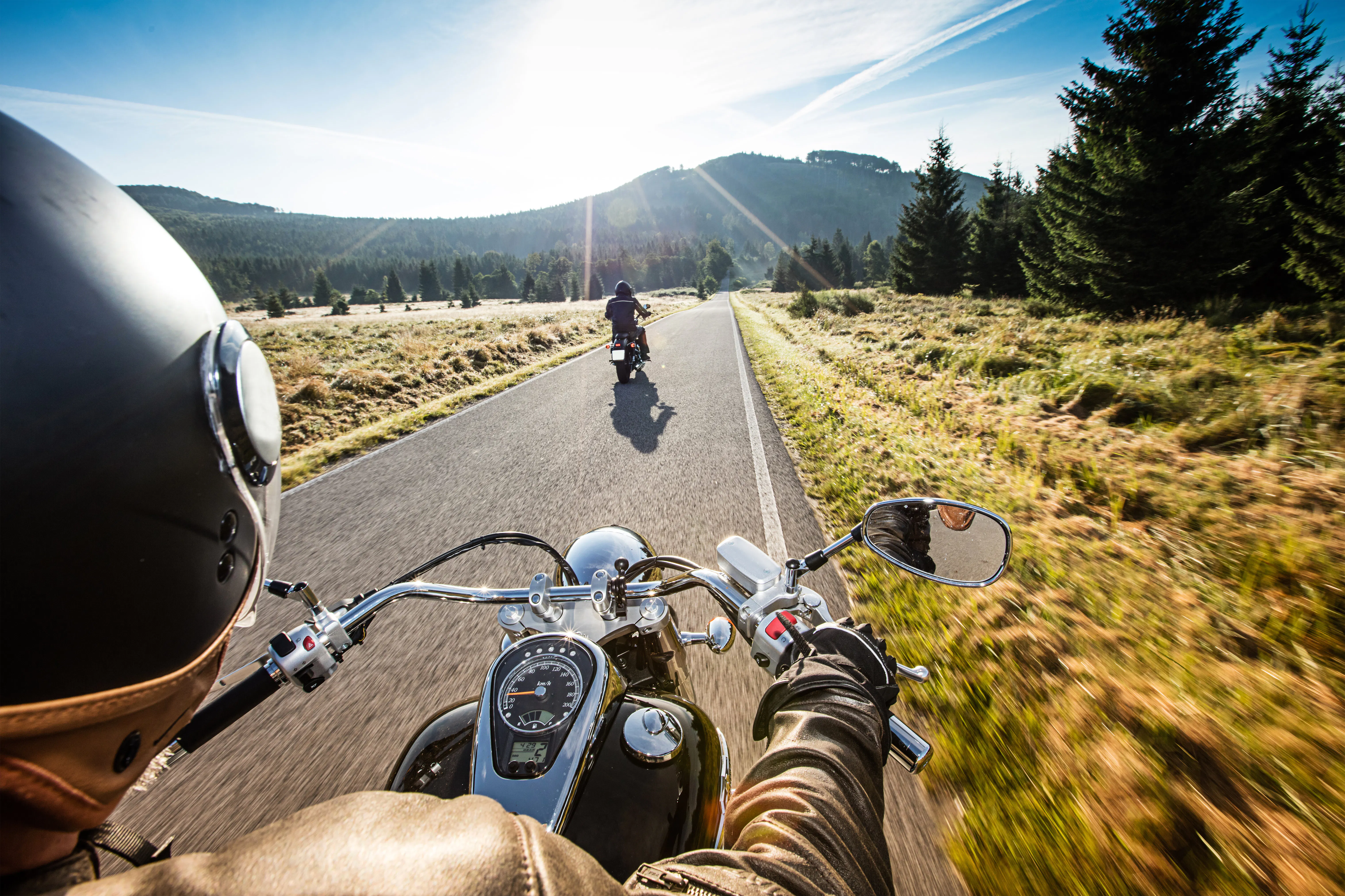 Dos personas en motocicletas recorriendo un sendero pintoresco por la naturaleza en un día soleado