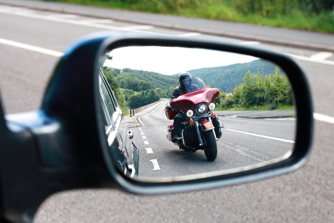 picture of a motorcycle rider on road from the view of a car side mirror motorcycle safety