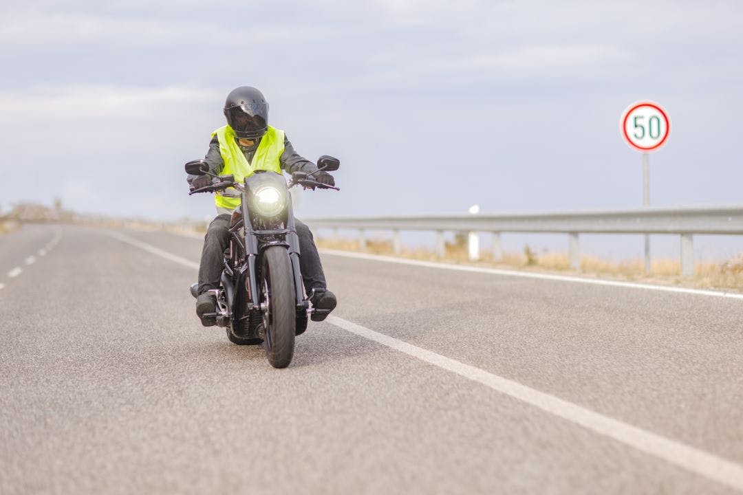 picture of a man riding a motorcycle with a reflective vest on for added visibility guide to motorcycle protective gear