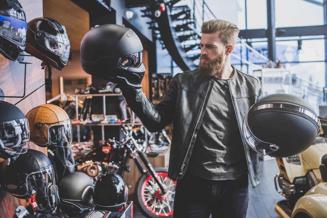 picture of man looking at different types of motorcycle helmets guide to motorcycle protective gear