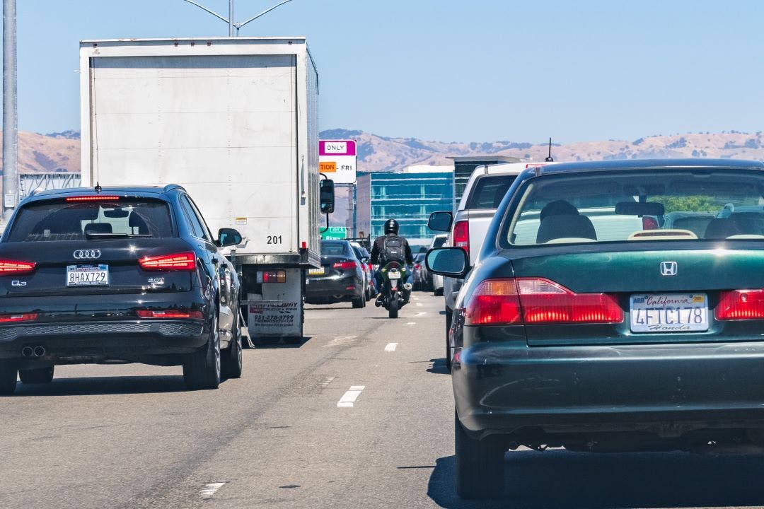 picture of a crowed highway in california with a motorcycle rider splitting lanes with the traffic california motorcycle law