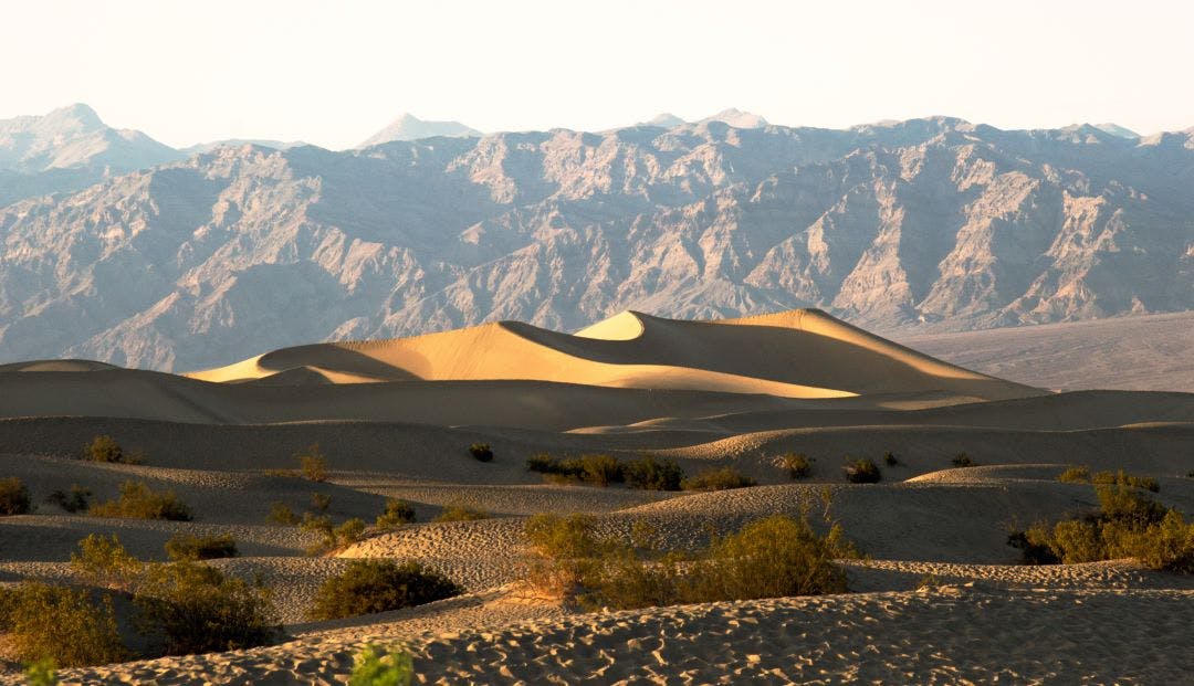scenic picture of mesquite flat sand dunes with mountains in the background road trip from las vegas to death valley