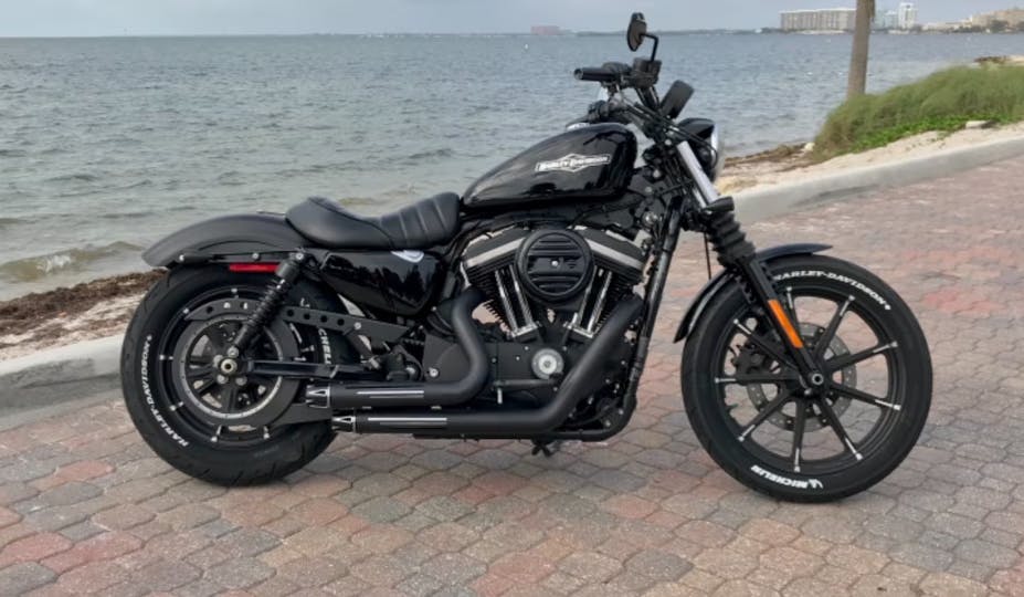 Picture of a harley davidson iron 883 sitting on next to the ocean