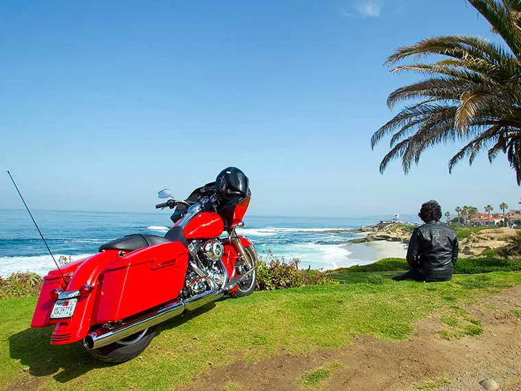 Motocicleta cruzera Harley-Davidson estacionada en un acantilado panorámico de California.
