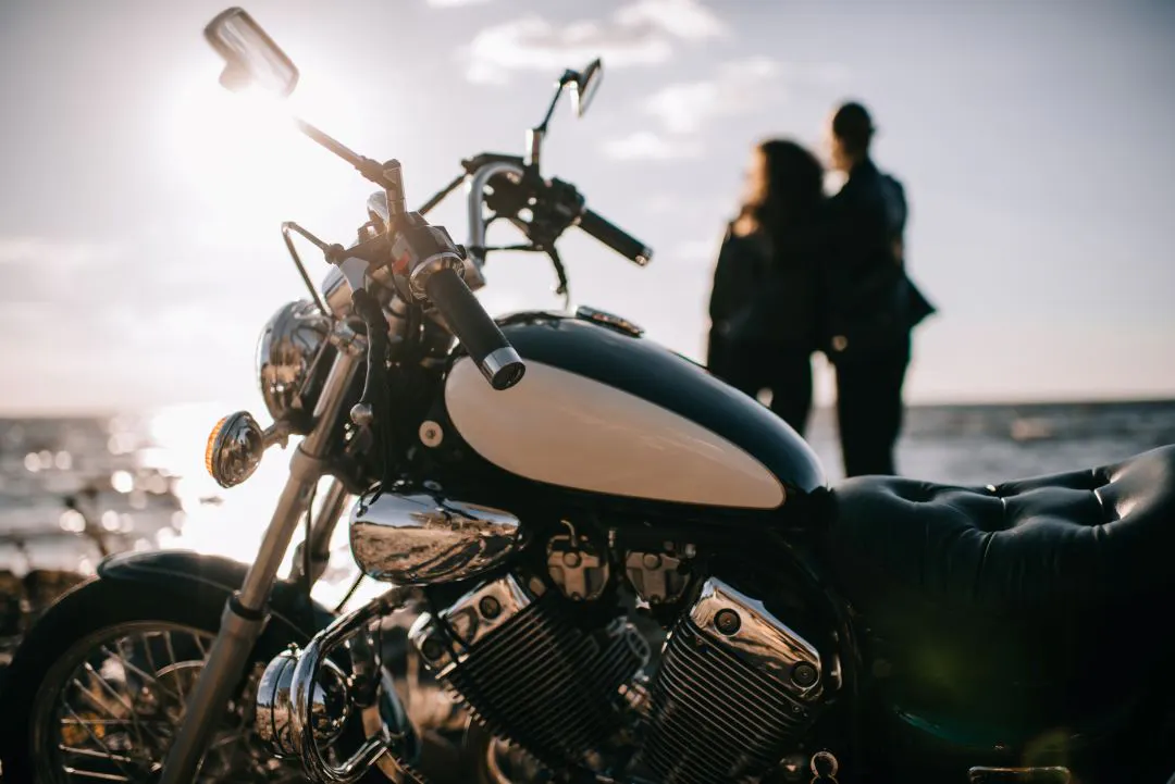 Foco seletivo de motocicleta chopper clássica e casal olhando para o mar ao fundo