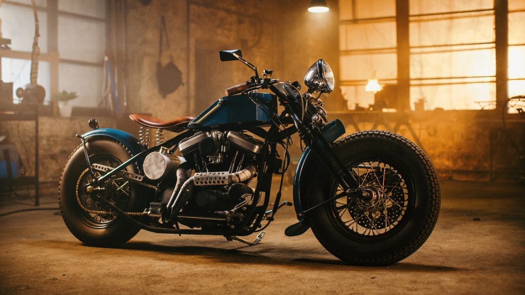 Custom Bobber Motorbike Standing in an Authentic Creative Workshop. Vintage Style Motorcycle Under Warm Lamp Light in a Garage Greatest Motorcycles of the Last 100 Years (1925-2025)