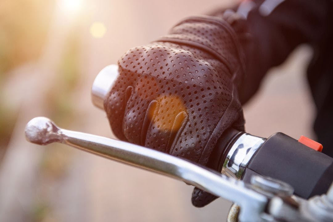 protective biker gloves on a motorcycle wheel Essential Florida Riding Gear for the State’s Unique Climate