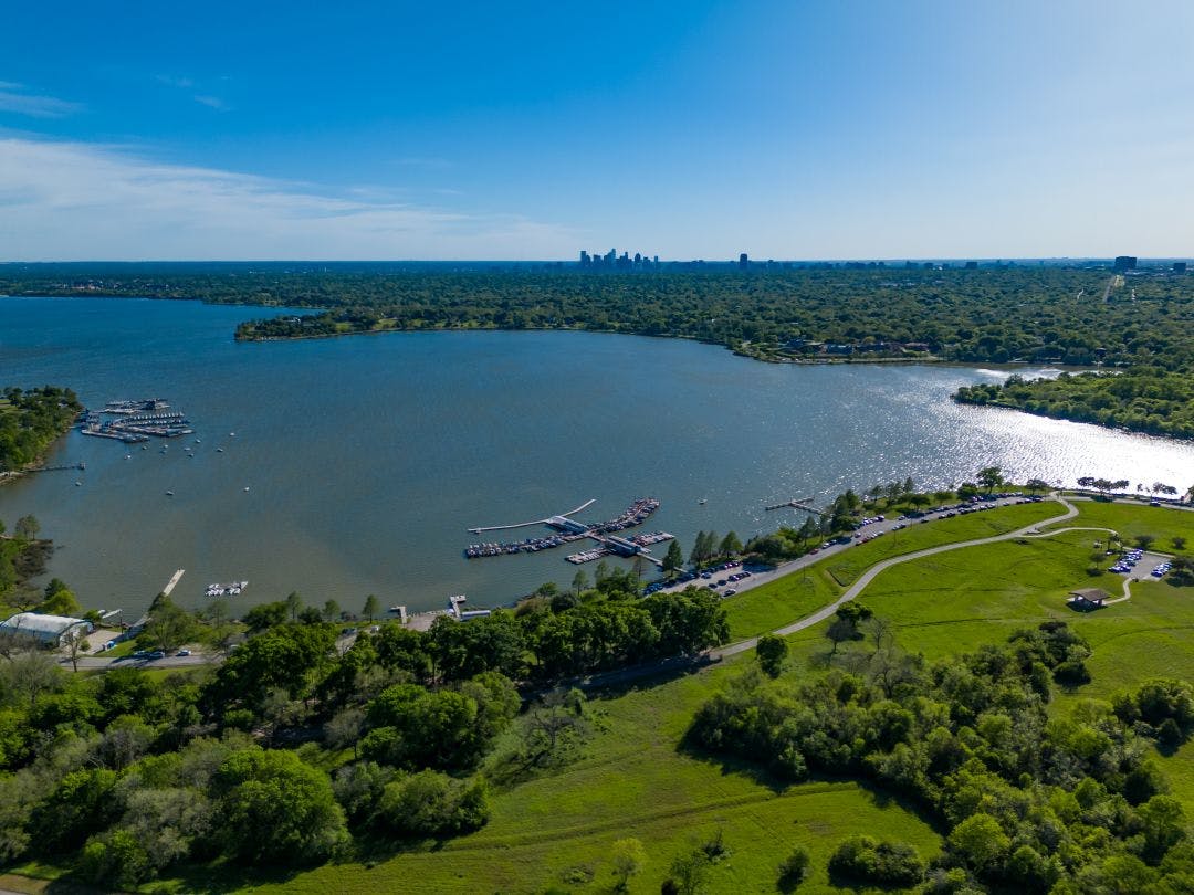 Dallas White Rock Lake Park and marina and Dallas skyline with blue sky and greenery Dallas Indian Motorcycle Rentals on Riders Share