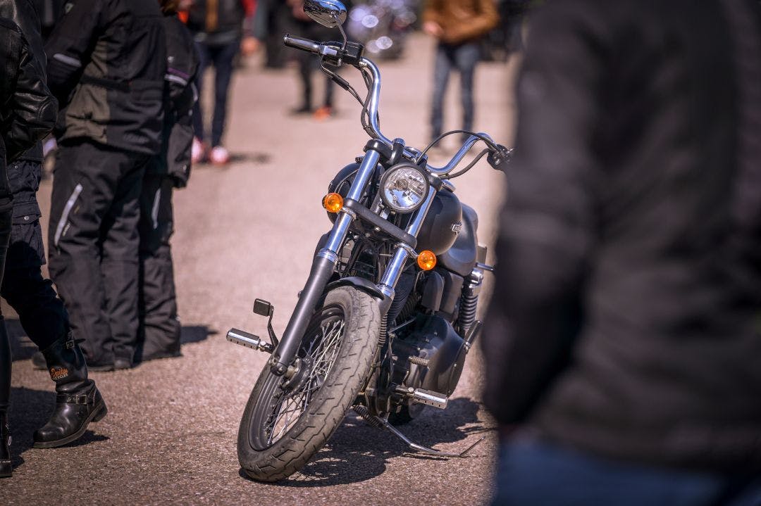 Motorcycle standing among people at a biker show How to Meet New People in the Motorcycle Community