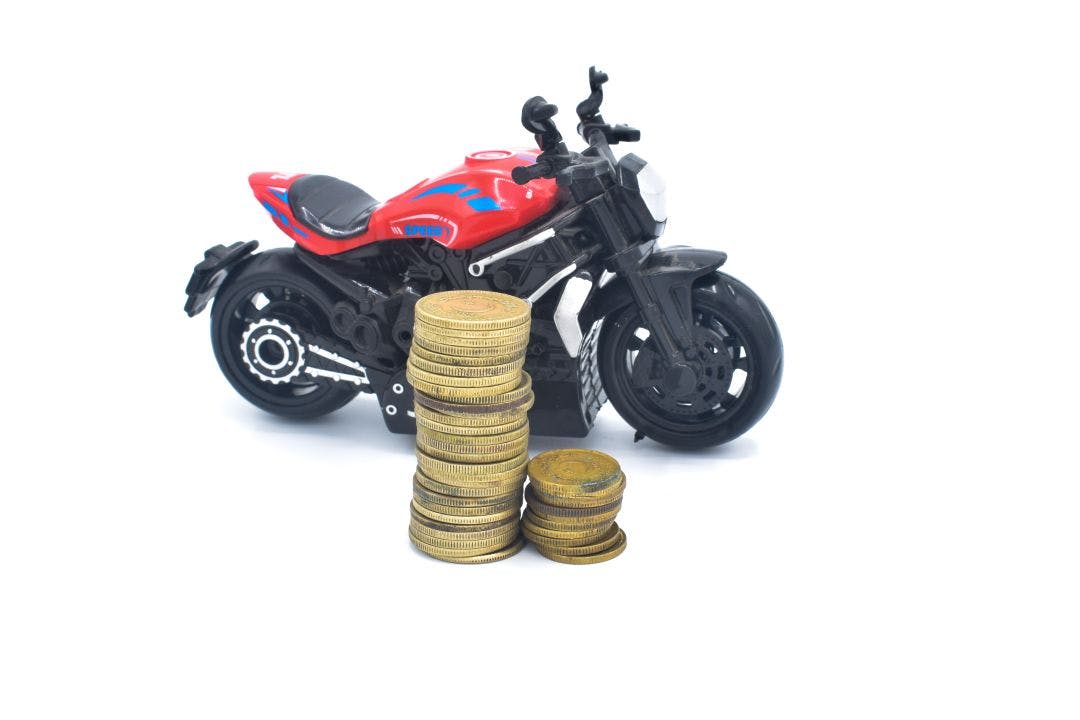 image of stack of coins with motorcycle toy How Much is Motorcycle Insurance? What to Expect