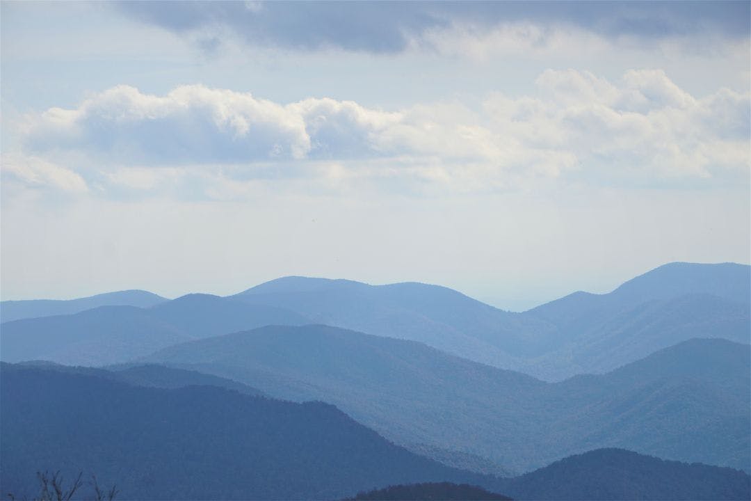 The fantastic view from Brasstown Bald mountain ( the highest mountain in Georgia) on a hazy day, mountains looks silhouette with white fluffy clouds and blue sky, North Georgia in USA Best Motorcycle Rides in Georgia