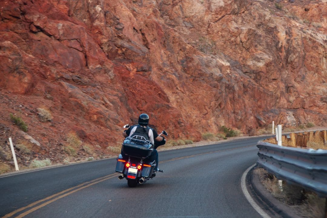 Motorcycle trip across America. Couple of bikers rides along the highway against the backdrop of rocks, rear view Guide to International Motorcycle Riding & Rentals in the USA