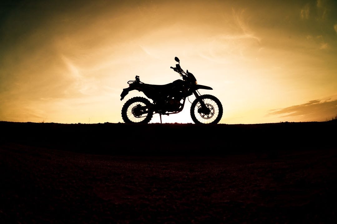 picture of a silhouette of a motorbike against a sunset best motorcycles under 300cc