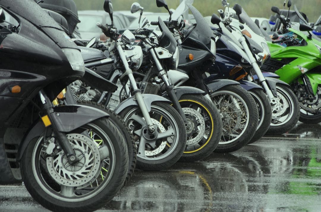 a row of different motorcycles parked on a wet asphalt parking lot choosing your second bike