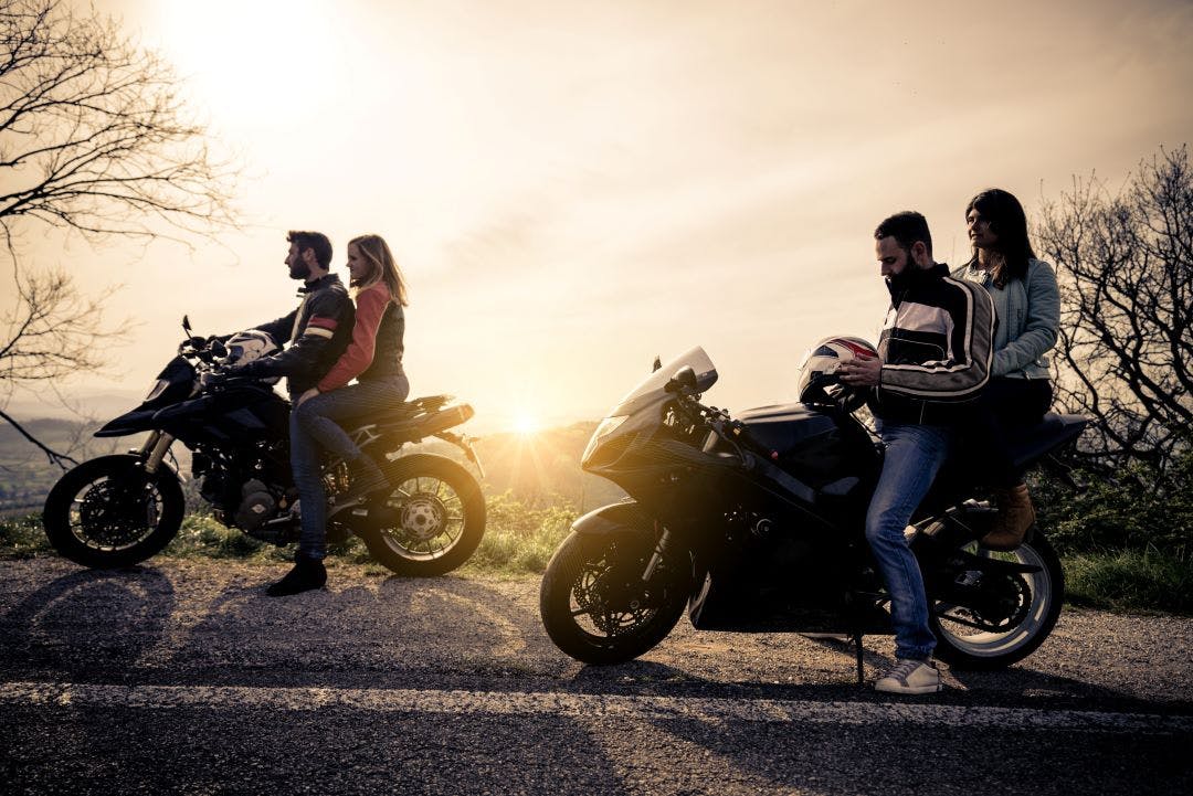 two motorcycles riders with passengers sitting on side of road on their bikes what size motorcycle do i need