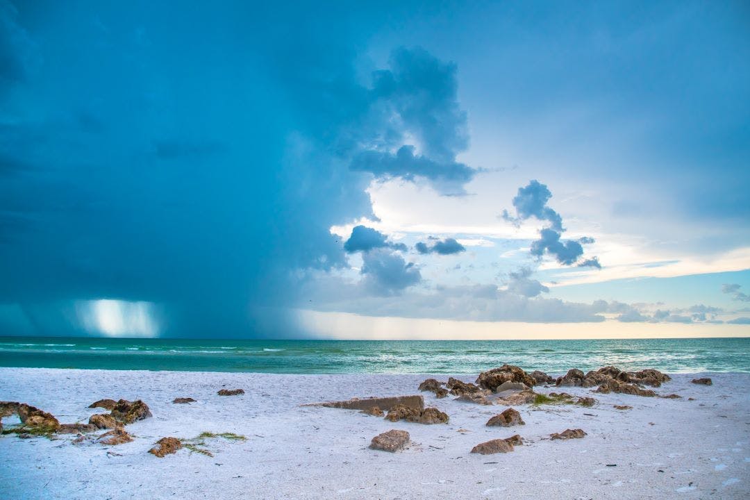 Siesta Key Florida Scene of the beach near Siesta Key Village at dusk as a storm appears in the distant sky cool blue turquois water along the rock studded shore best florida day trips