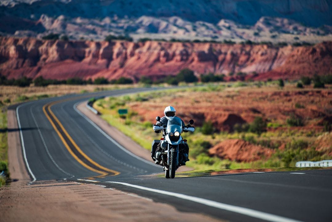 motorcycle riding on empty road with mountains in backgrounds San Diego Airbnb for Motorcycles: Riders Share